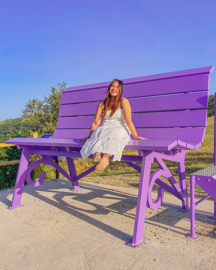 ragazza felice seduta sulla panchina gigante lilla di Casalgrande a Reggio Emilia