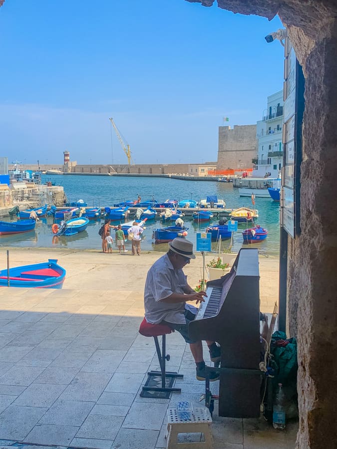 pianista suona il piano nel porto antico di Monopoli da non perdere assolutamente in una gita di un giorno