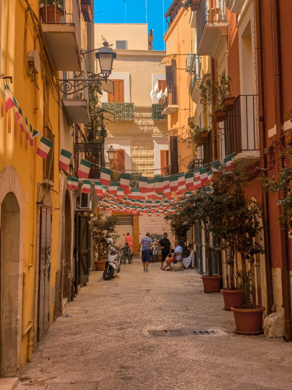 vicolo di Bari vecchia decorato con bandiere Italia da vedere un giorno a Bari